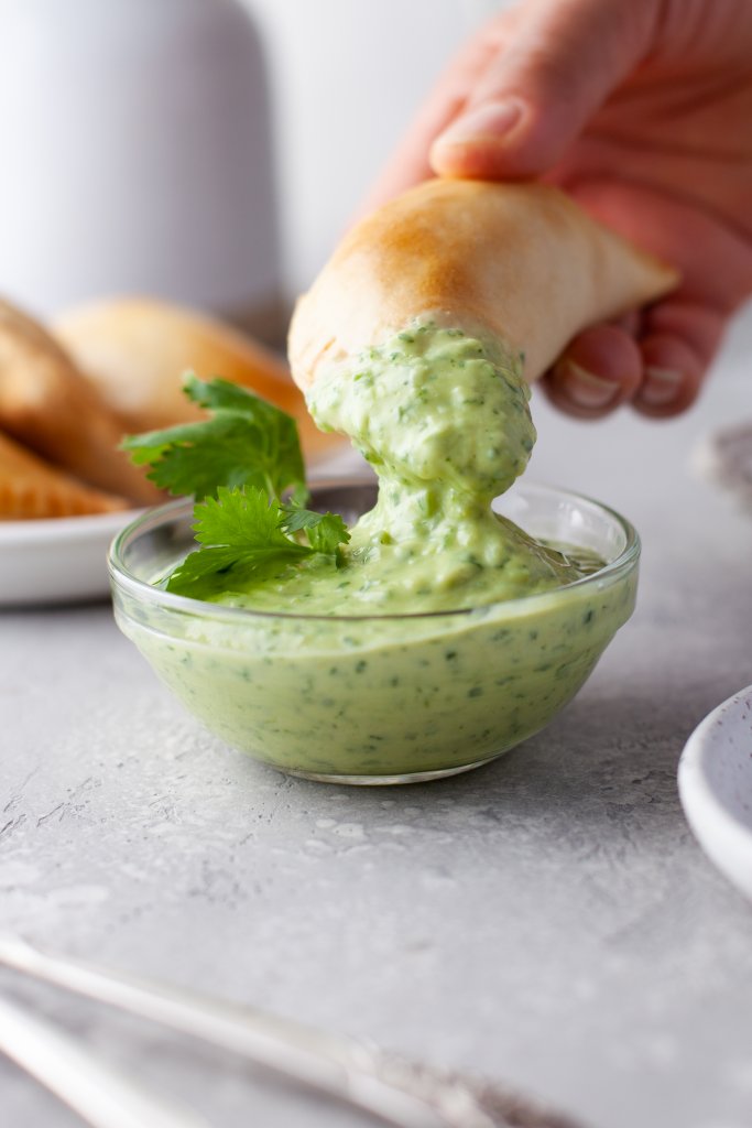 dipping an empanada in sauce