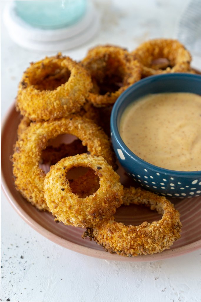 air fryer onion rings on a plate with sauce