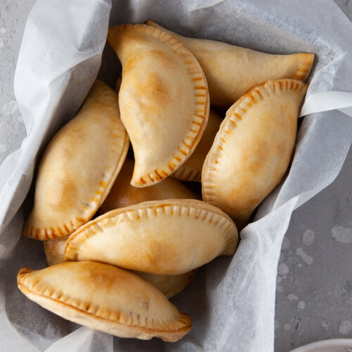 chicken empanadas in a basket with parchment paper