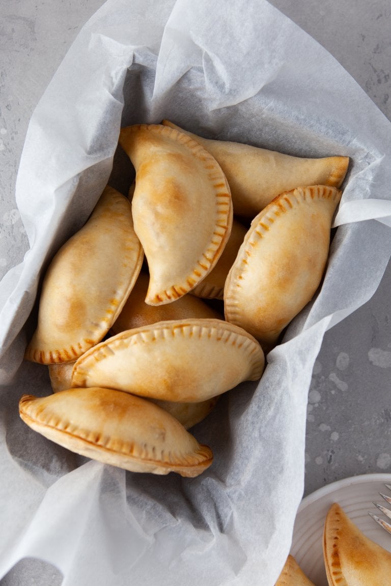 chicken empanadas in a basket with parchment paper