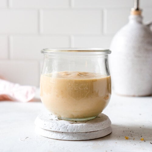 miso tahini sauce in a glass jar on a coaster