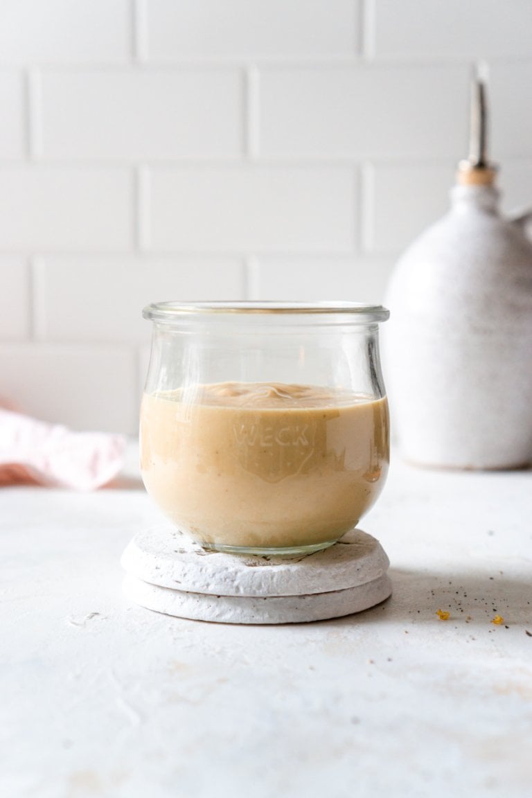 miso tahini sauce in a glass jar on a coaster