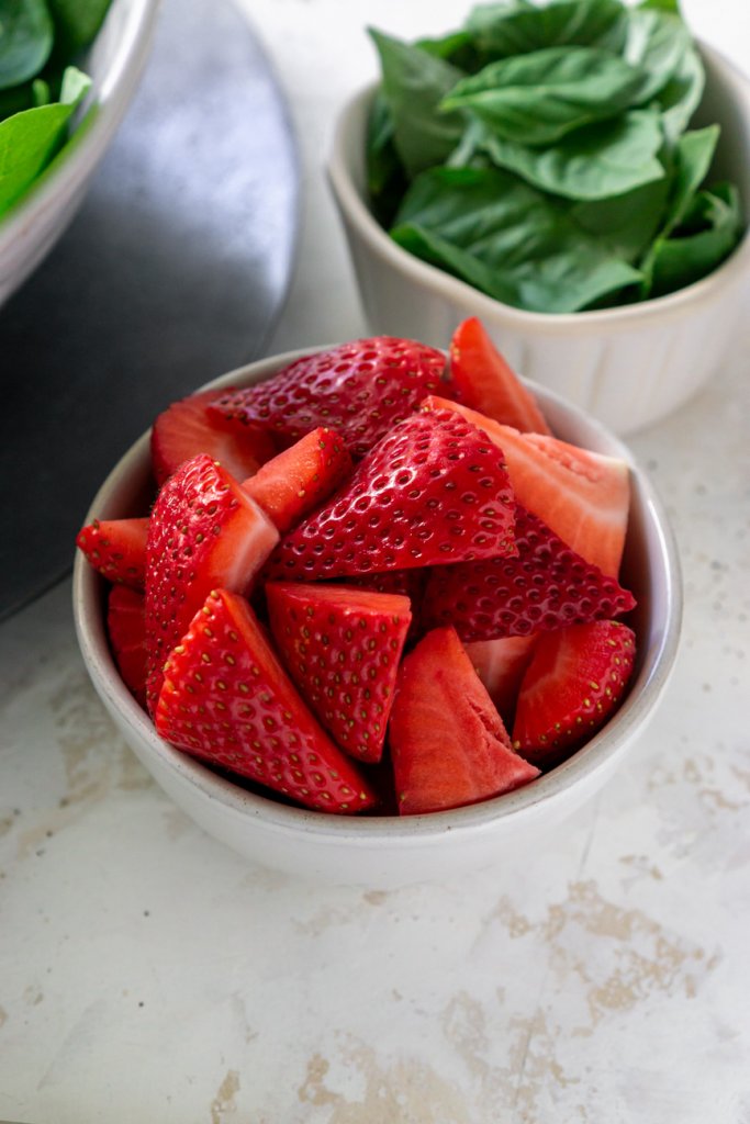 two bowls with sliced strawberries and basil