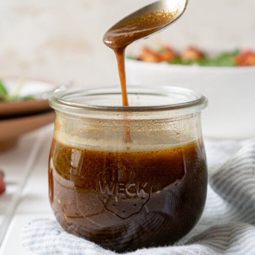 balsamic dressing dripping off a spoon into a glass jar