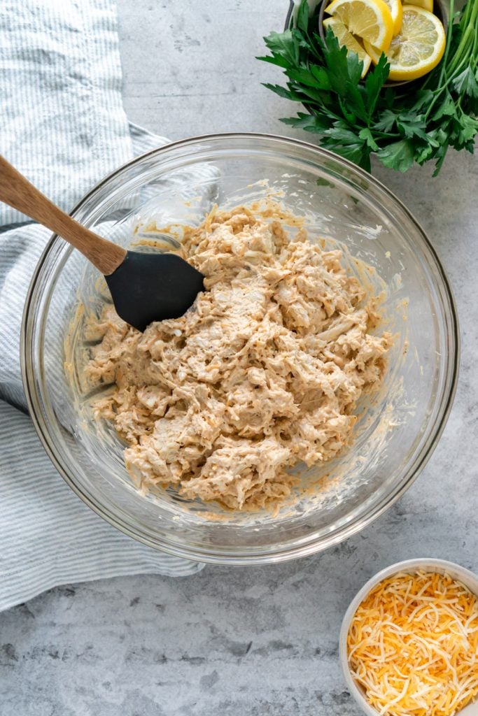 crap dip fully mixed together in a clear glass mixing bowl with a spatula in it.