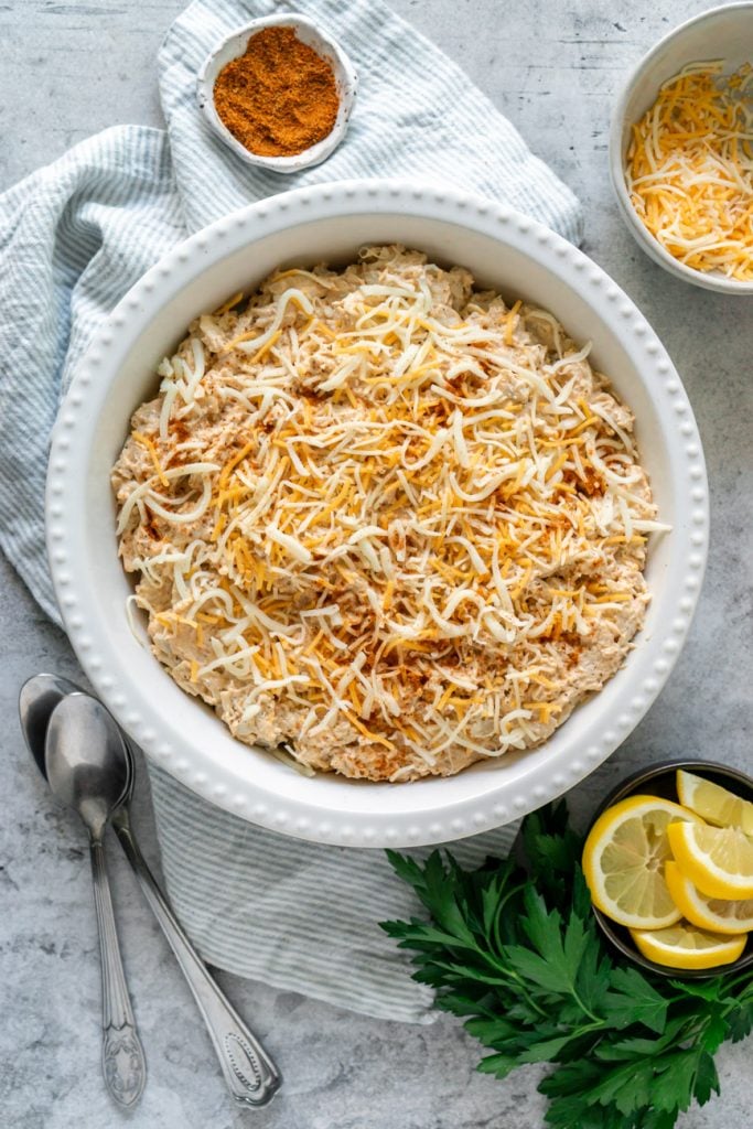 Maryland crab dip in a white baking dish with shredded cheese on top.