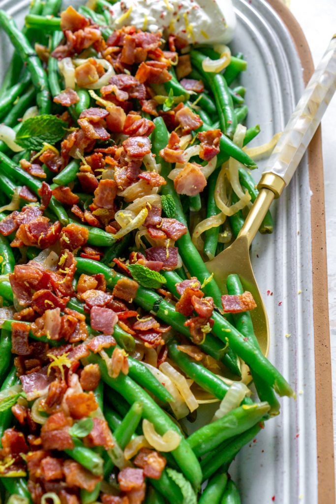 green beans with bacon on a plate with a serving spoon 