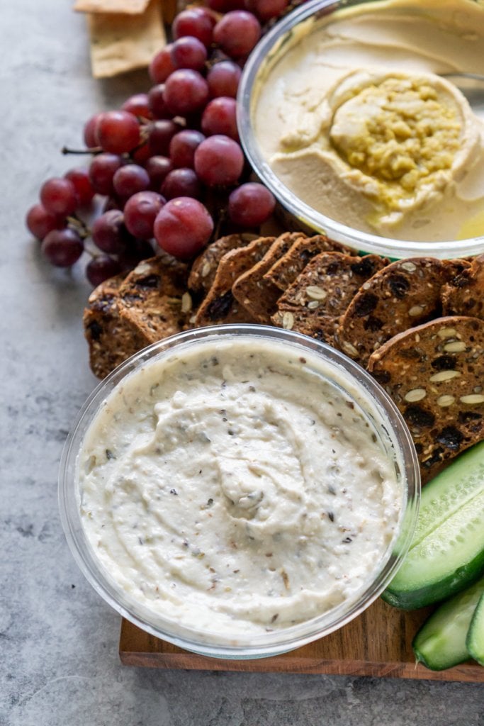 feta dip on a wood board with grapes and hummus