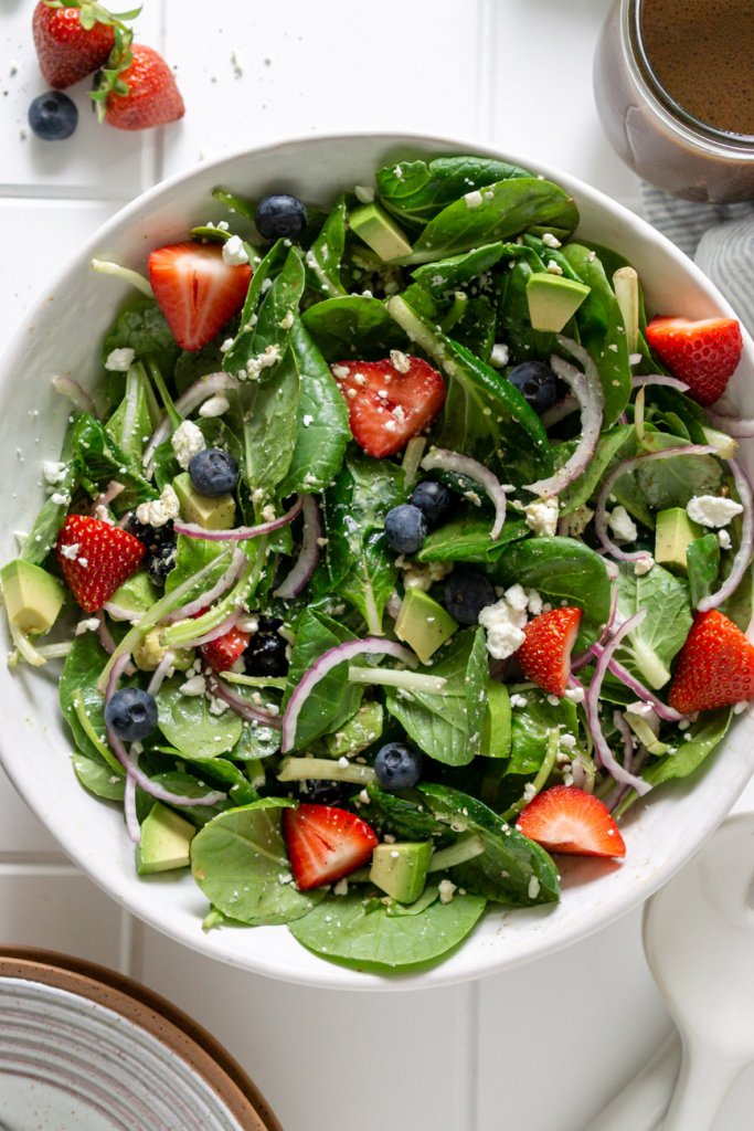 strawberry spinach salad in a large white bowl