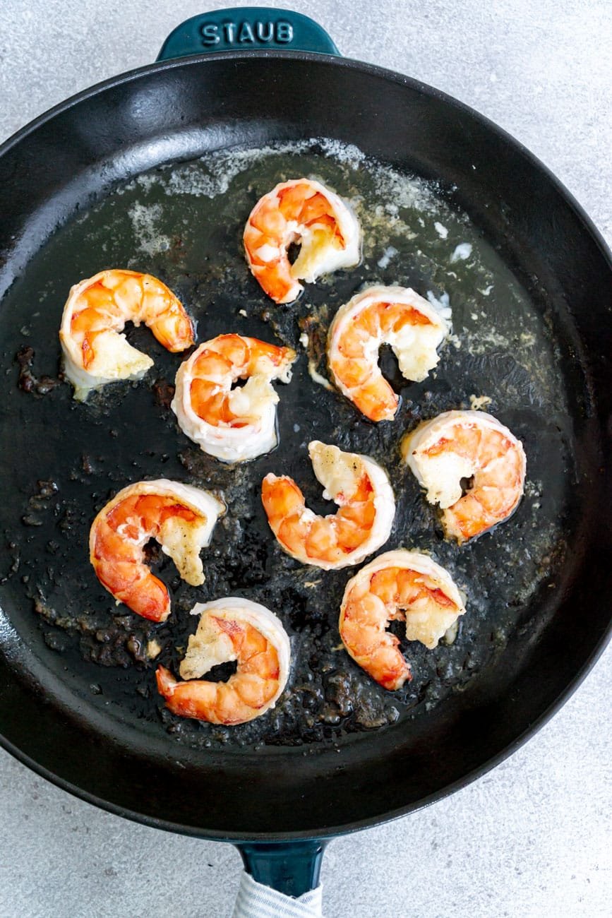 Shrimp and garlic sautéing in a cast iron skillet.