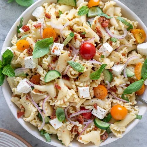 gluten free pasta salad in a serving bowl with basil leaves