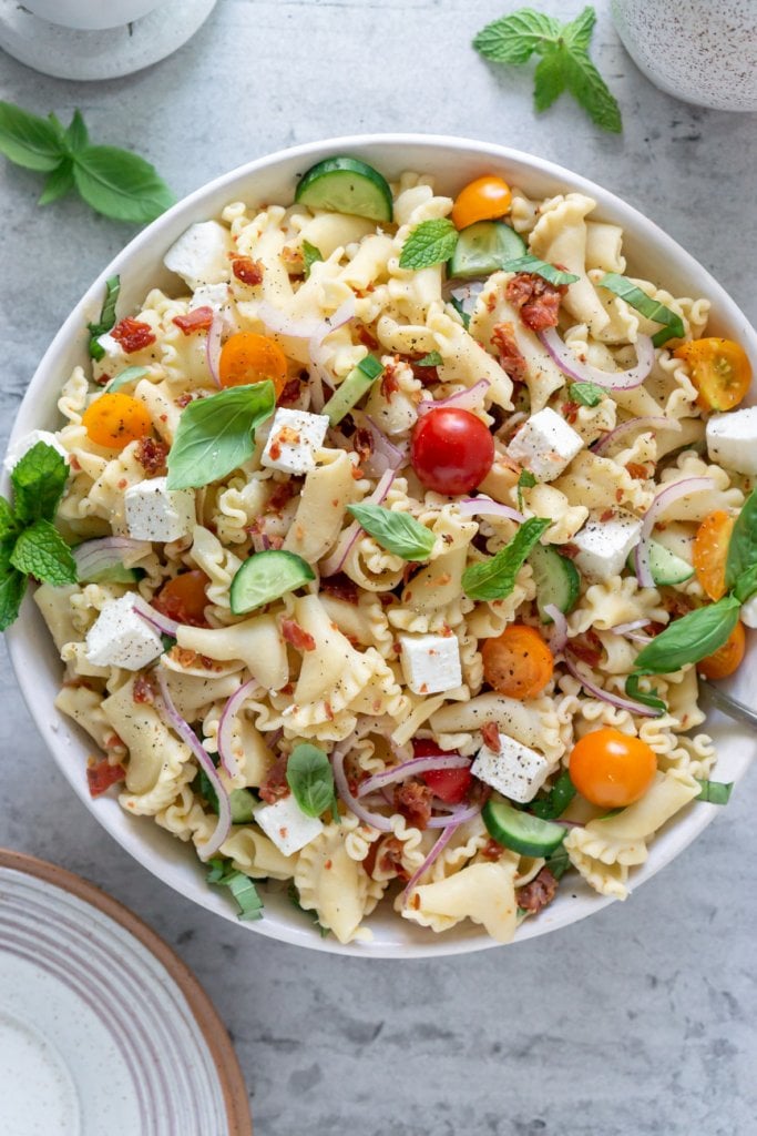 gluten free pasta salad in a serving bowl with basil leaves
