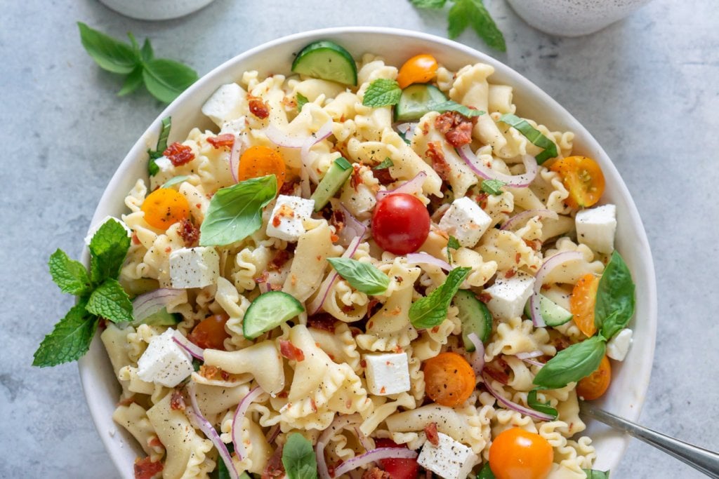 A bowl of Mediterranean pasta salad with a fork in it.