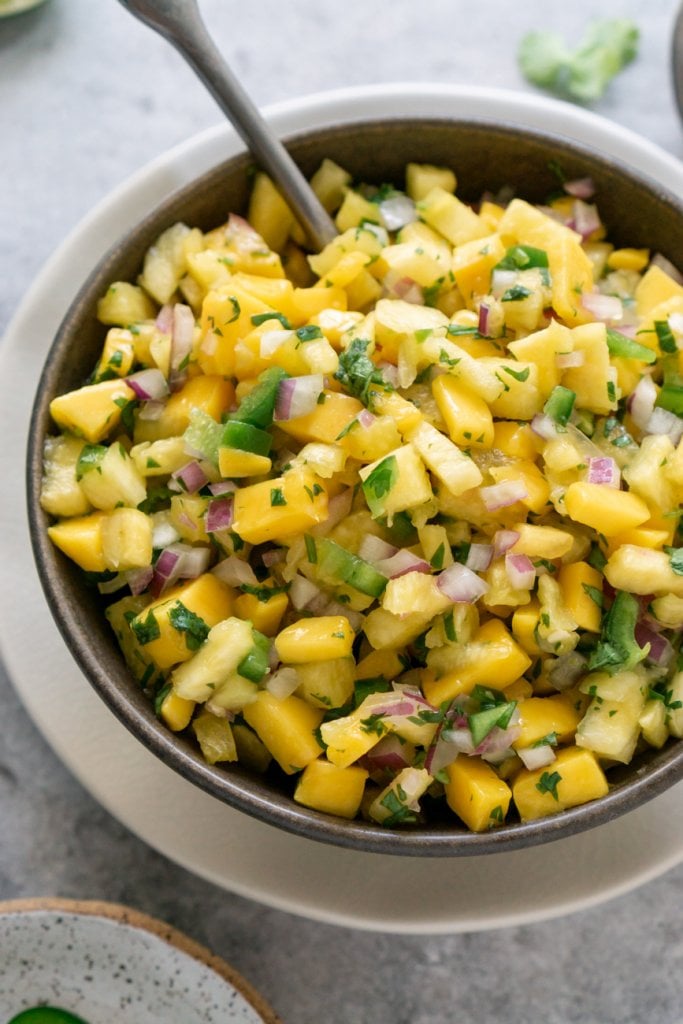 pineapple mango salsa in a brown bowl with a spoon