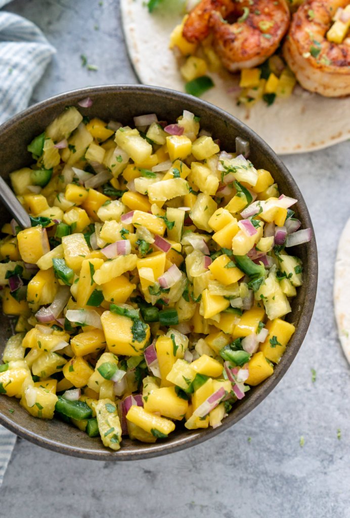 mango pineapple salsa in a bowl and a shrimp taco