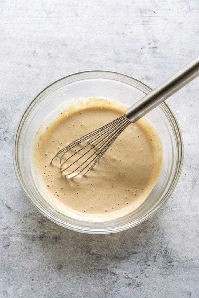 remoulade sauce in a glass mixing bowl with a whisk