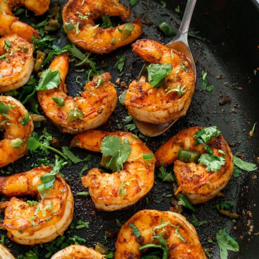 Tequila lime shrimp garnished with cilantro in a cast iron skillet.