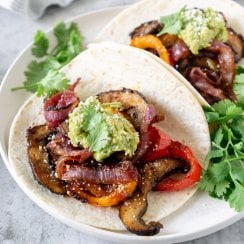 two vegetarian fajitas tacos on a plate with cilantro