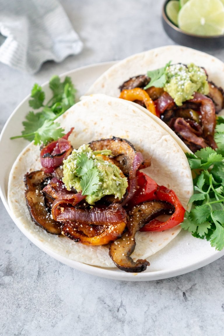 two vegetarian fajitas tacos on a plate with cilantro