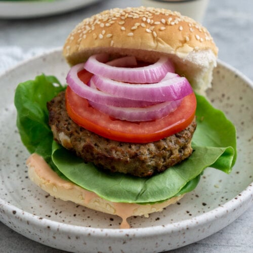 air fry frozen burger on a plate with lettuce, onions, and tomato