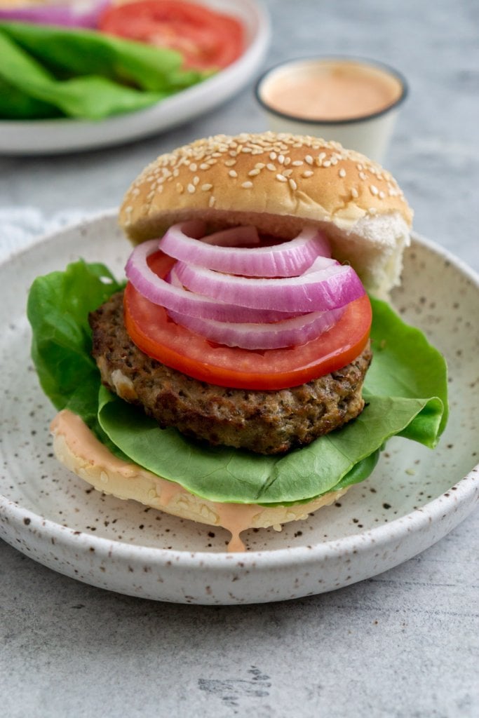 air fry frozen burger on a plate with lettuce, onions, and tomato