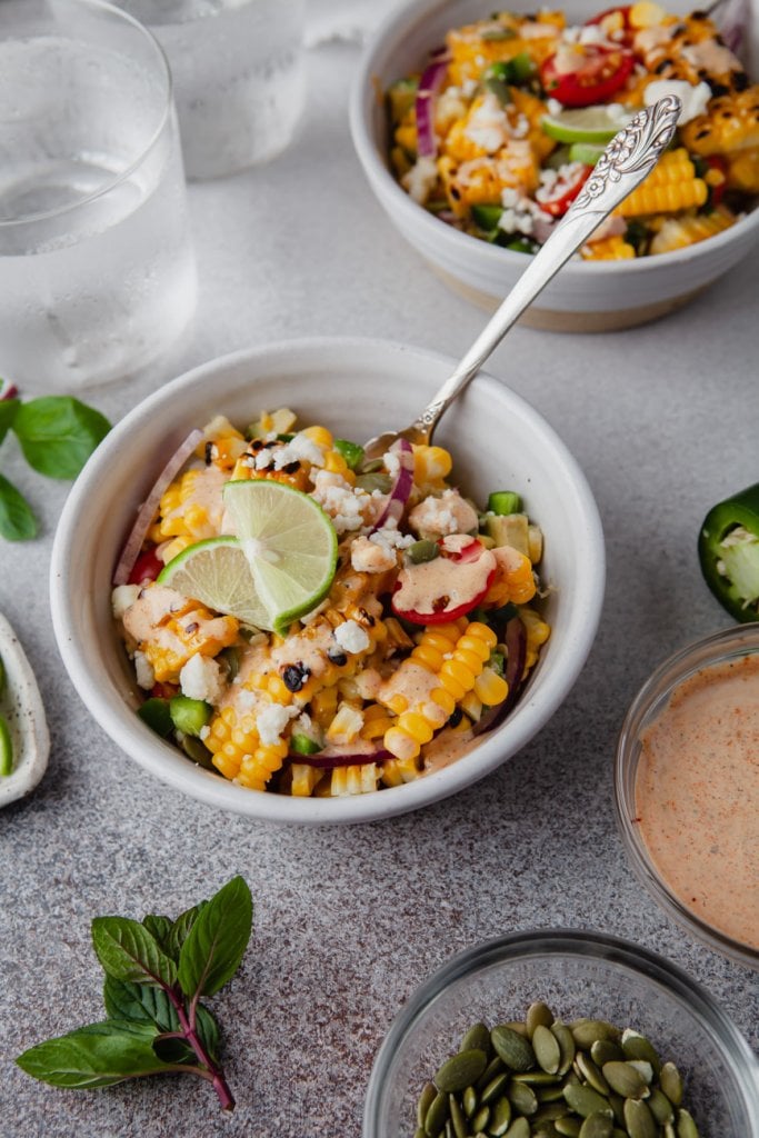 two small bowls with corn salad and a silver spoon