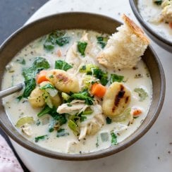 a bowl of chicken gnocchi soup with a piece of bread