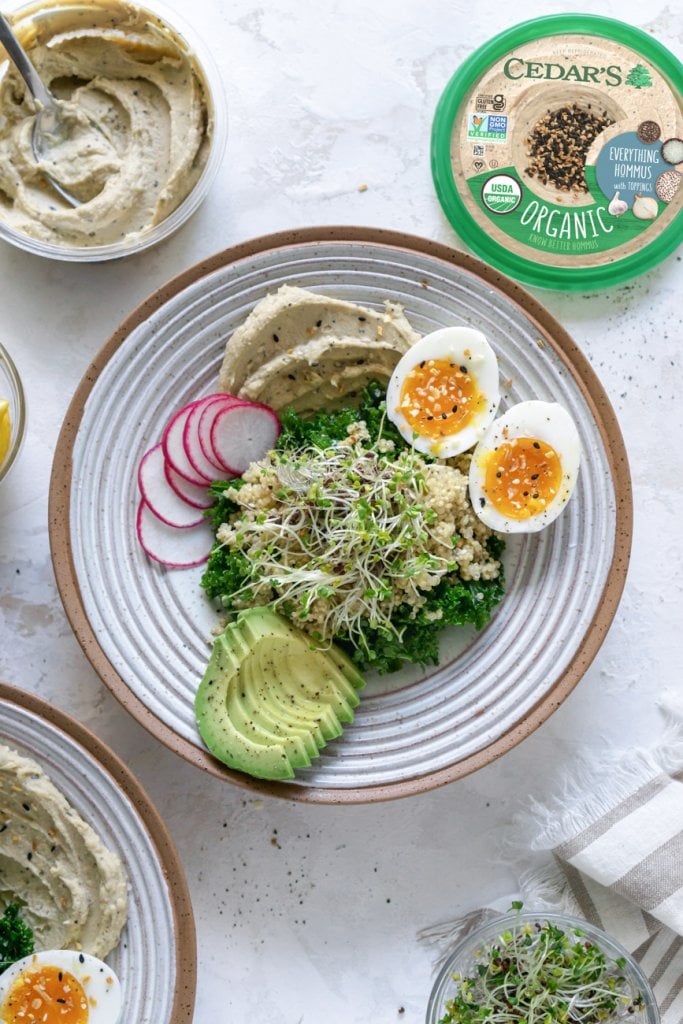 kale, sprouts, eggs, hummus avocado in a bowl, small bowls of ingredients off to the side