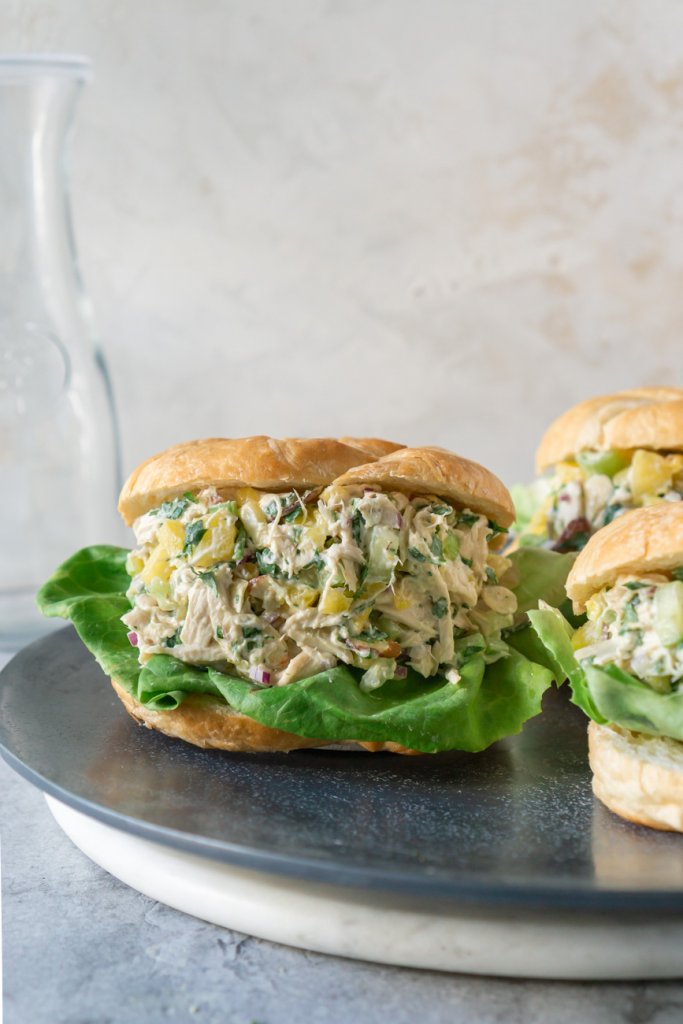 3 pineapple chicken salad croissant sandwiches on a grey plate