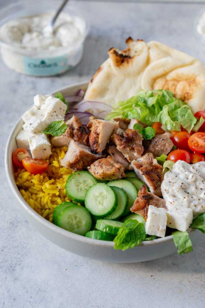 chicken shawarma bowl with a piece of naan and feta dip on the side