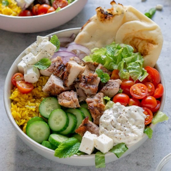 two chicken shawarma bowls with a napkin and bowl of salt