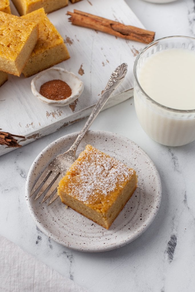 golden sweet cornbread on a white plate sprinkled with powdered sugar