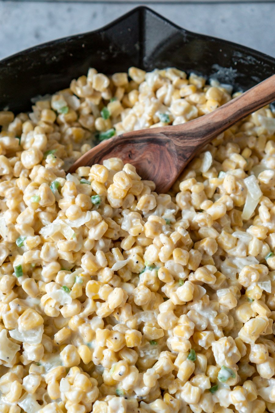 stirring creamed corn with a wooden spoon