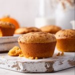 pumpkin cornbread muffin on a wood board with flowers behind