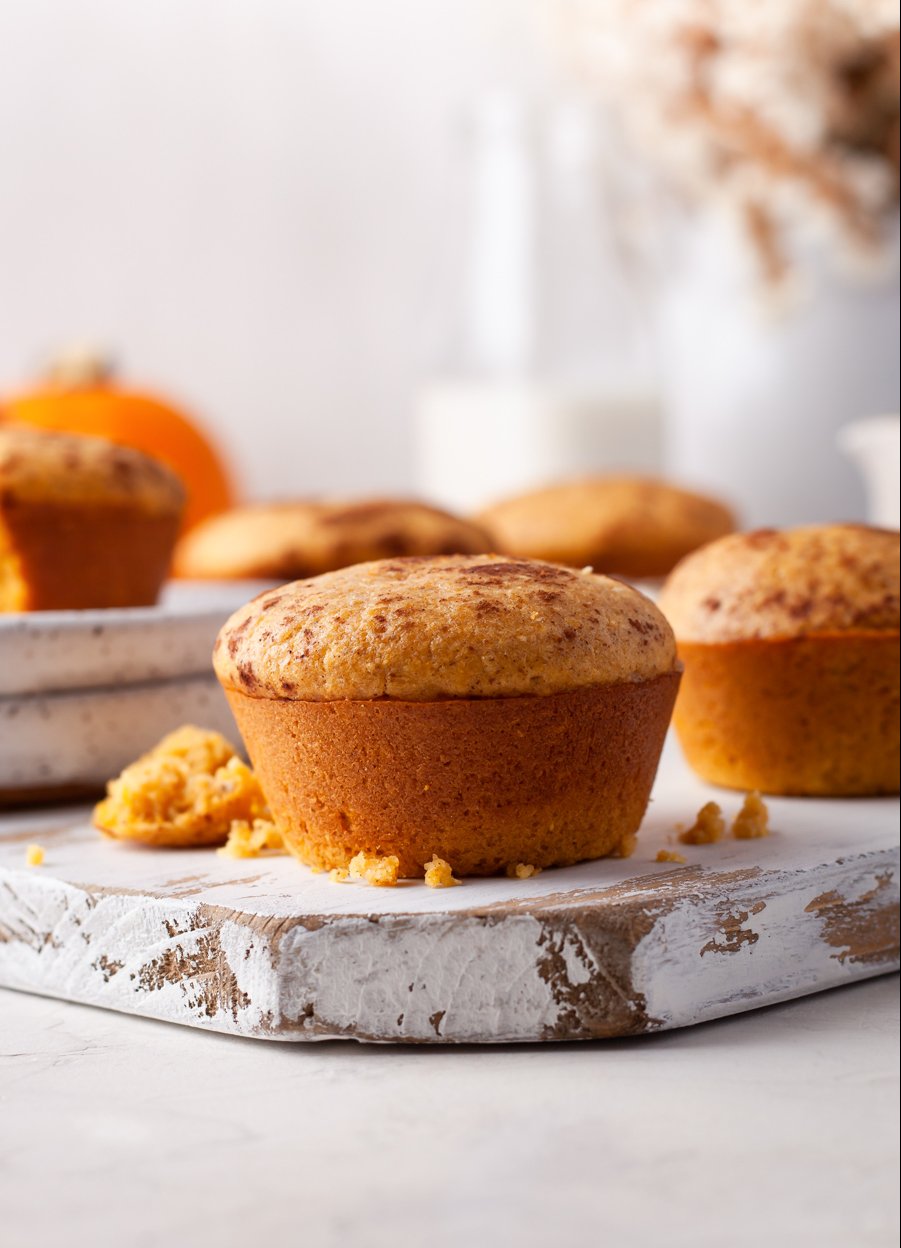 pumpkin cornbread muffin on a wood board with flowers behind