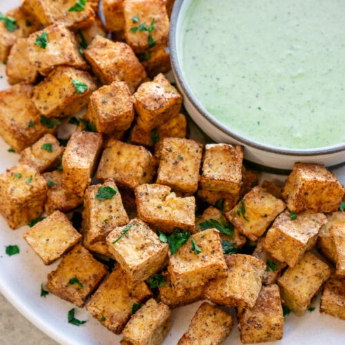 air fryer tofu on a white plate with a bowl of sauce