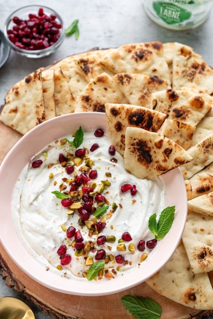 labneh dip in a pink bowl with naan dipped