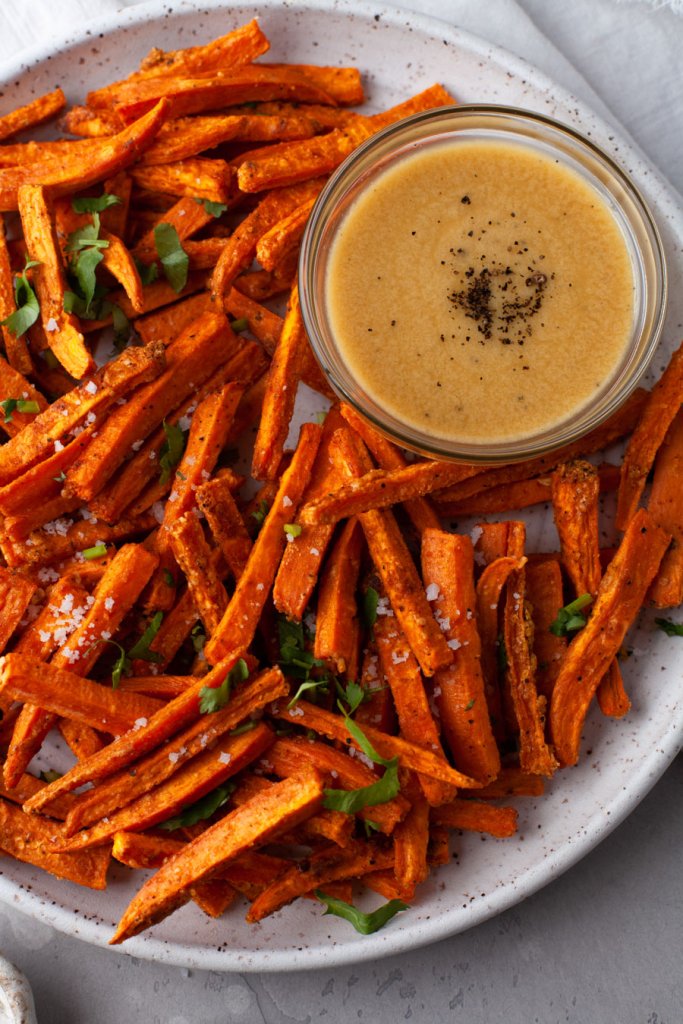 oven baked sweet potato fries on a white plate with dipping sauce