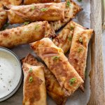 buffalo chicken egg rolls on a wood tray with ranch dipping sauce