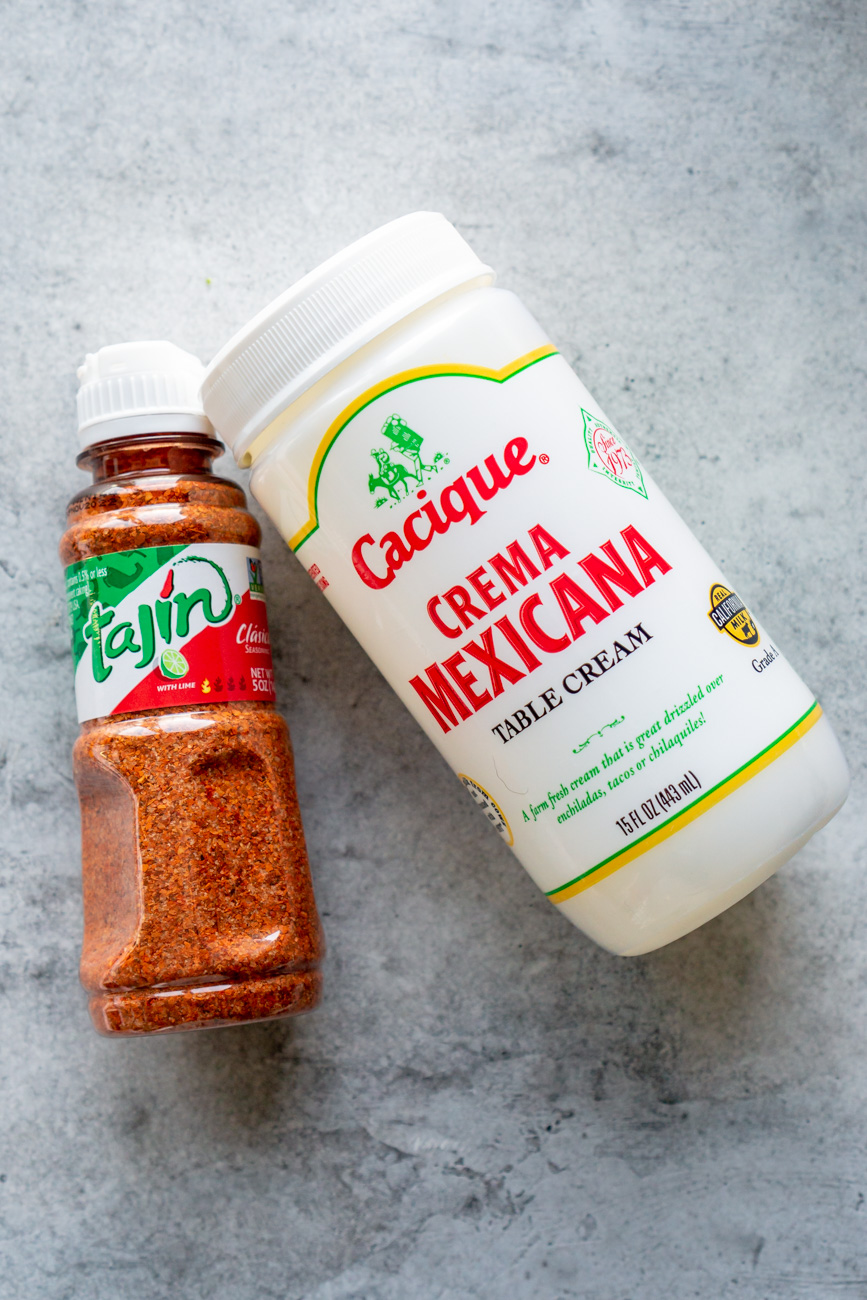 Tajin and Mexican crema on a grey table.