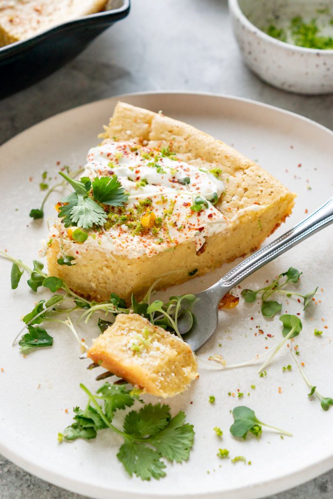 a slice of mexican cornbread on a plate with a bite on a fork