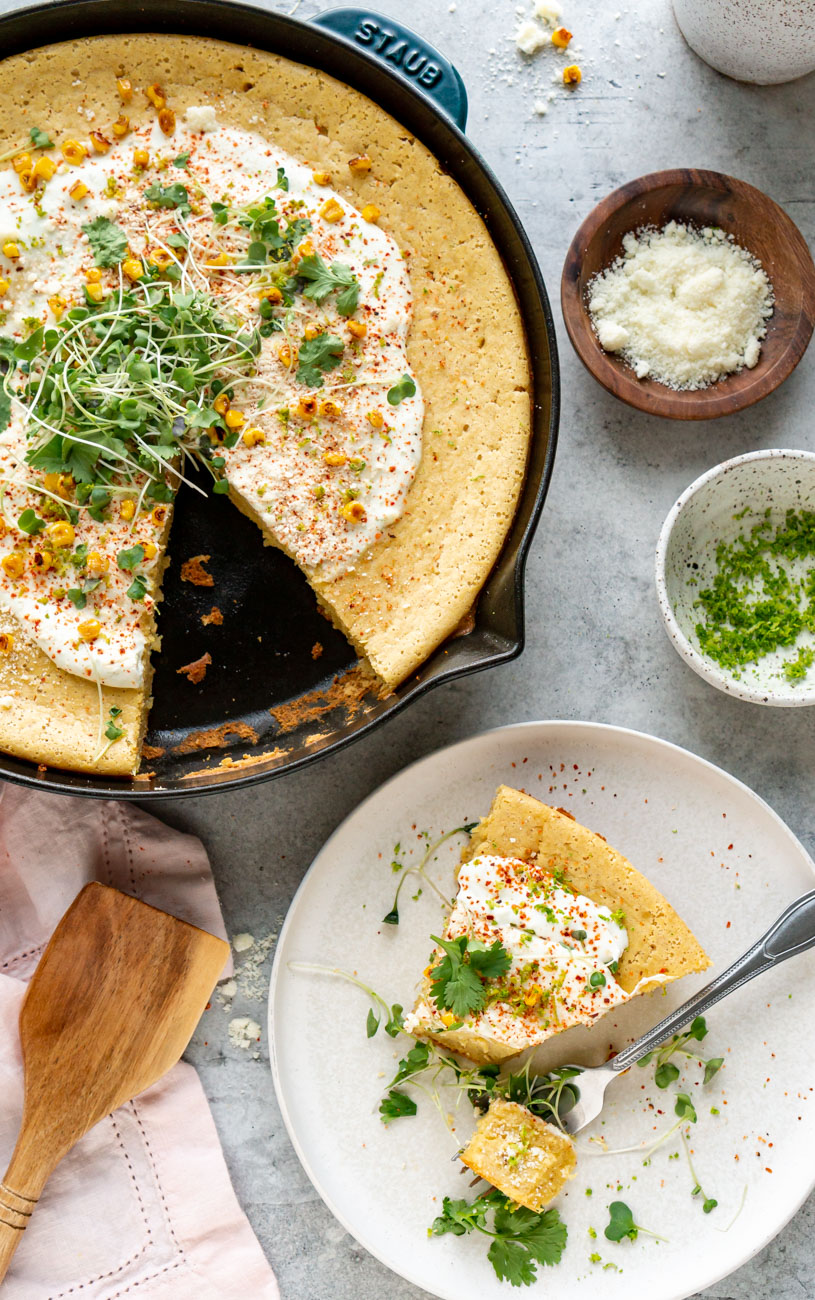 Mexican cornbread in a skillet and a slice on a white plate.