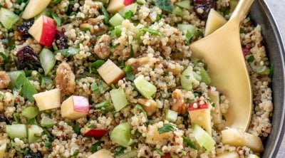 quinoa apple salad in a dark grey bowl with a gold spoon