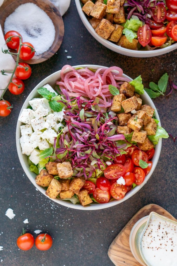 shawarma tofu salad in a bowl with tomatoes and tahini dressing on the side
