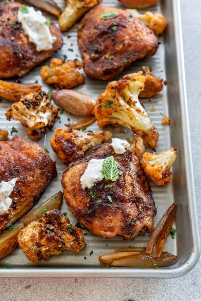 baked chicken thighs and cauliflower on a metal pan