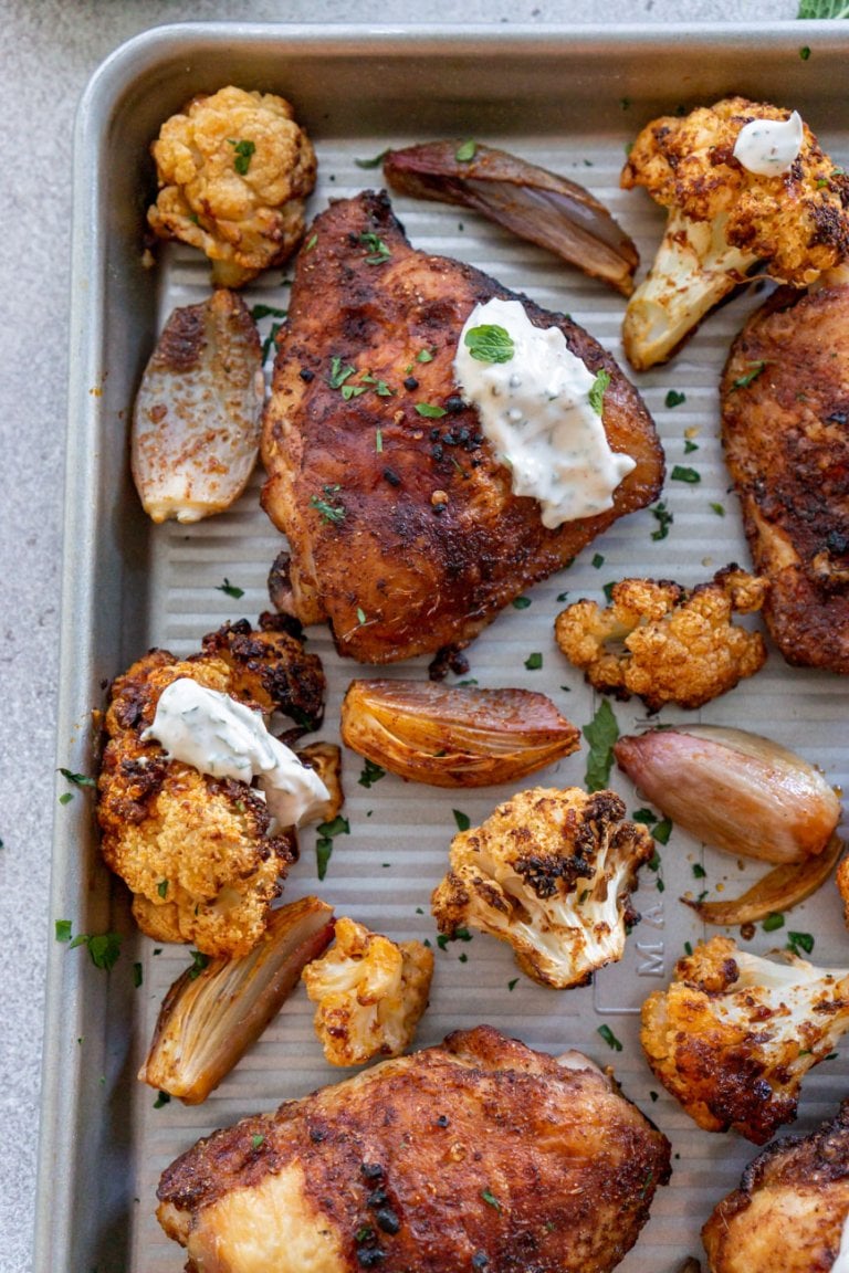 chicken and cauliflower on a sheet pan with yogurt sauce