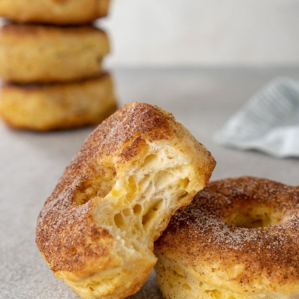 air fryer donuts, one with a bite taken and 4 stacked in the background