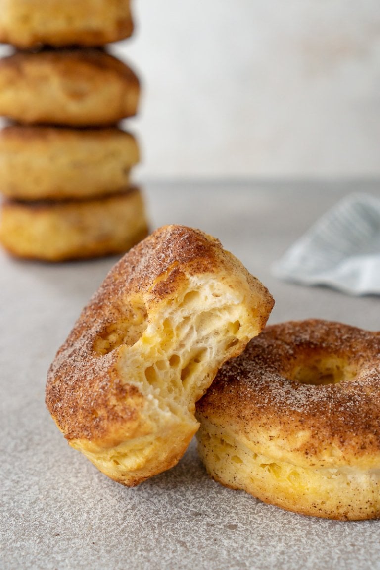 air fryer donuts, one with a bite taken and 4 stacked in the background