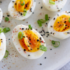 Air fryer hard boiled eggs sliced in half on a white plate.
