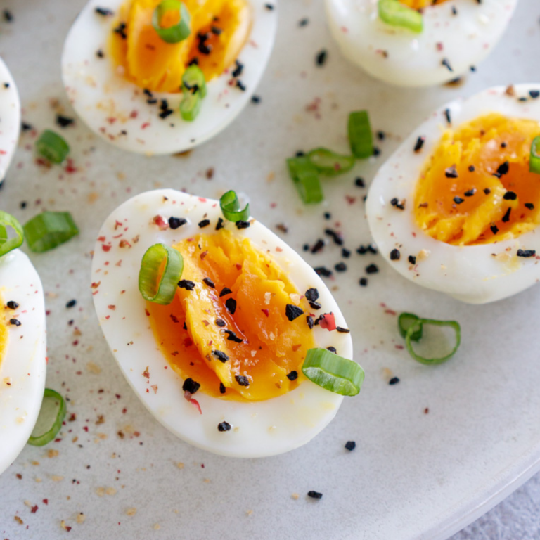 Air fryer hard boiled eggs sliced in half on a white plate.